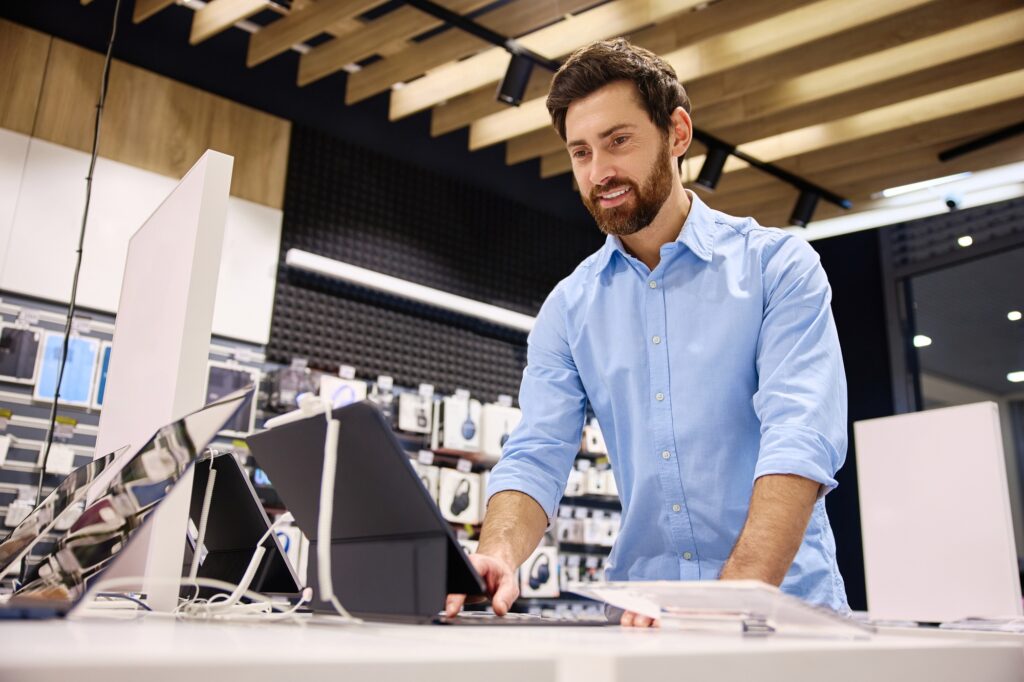 Man browsing Best Tech Deals 2025 in electronics store 