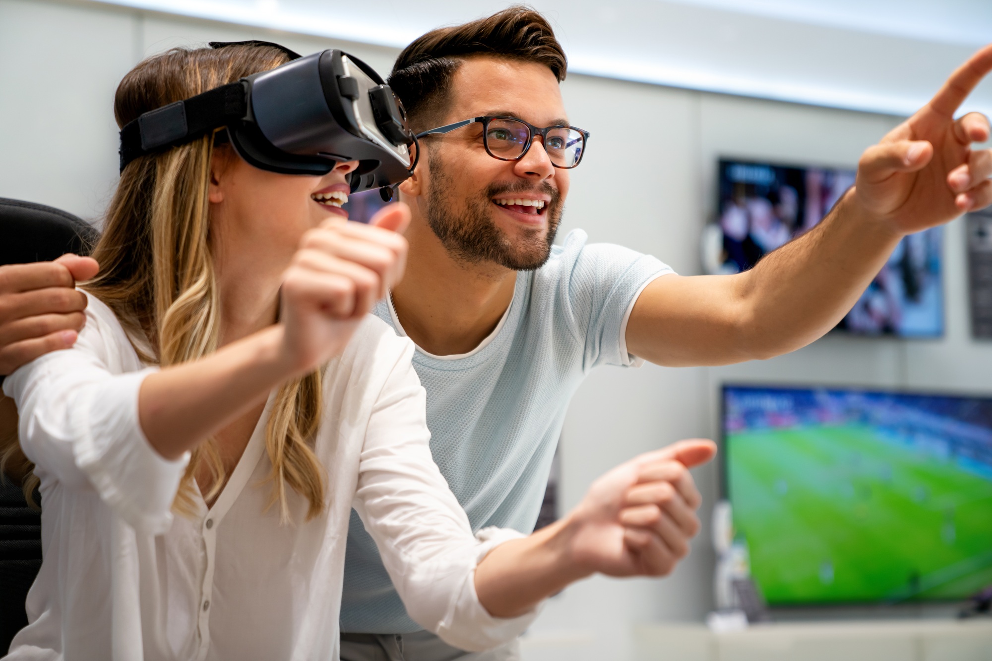 Young couple testing a VR headset in-store, enjoying immersive tech experiences while browsing the best electronics discounts available.