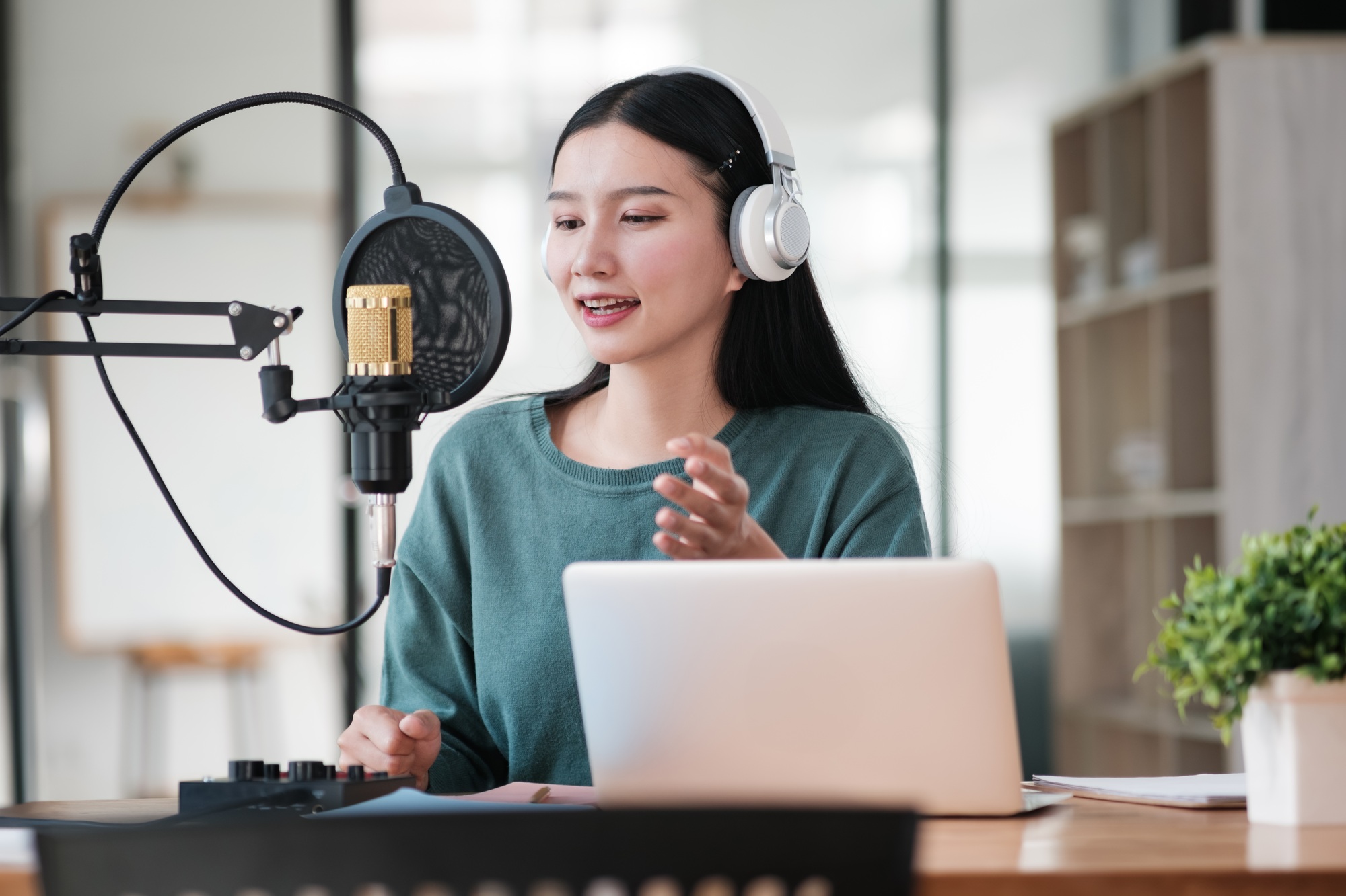 Young professional woman podcasting with a high-end microphone and webcam setup in a modern office — ideal for those looking to buy webcams and microphones