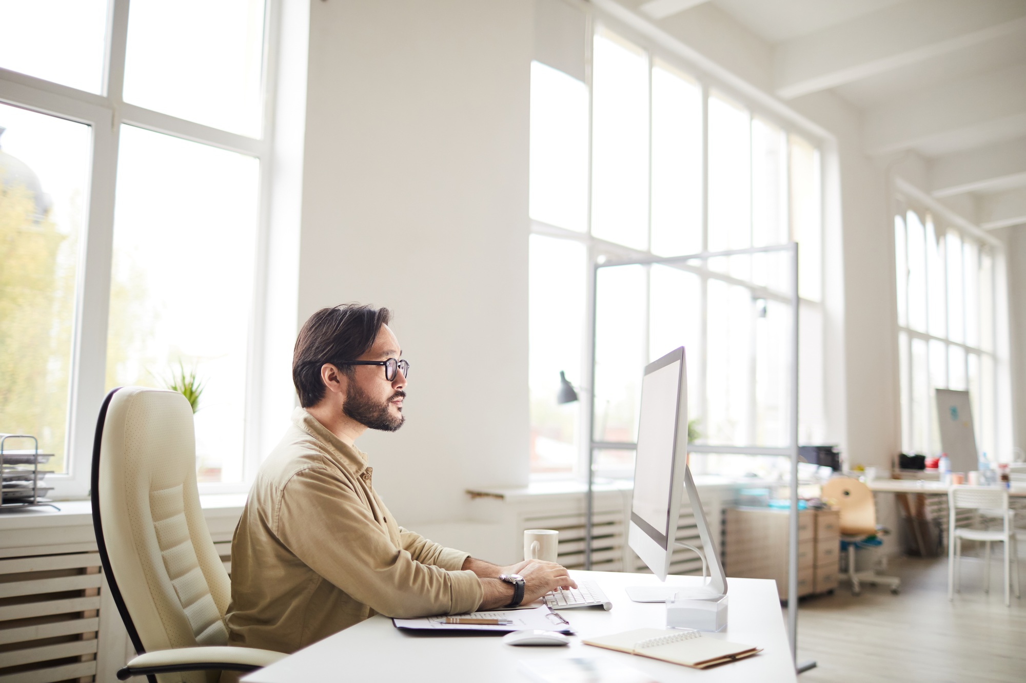 Corporate professional working at a modern desk on an all-in-one computer in a bright office setting—ideal visual for “Buy All-in-One Computers” branding or ads. 