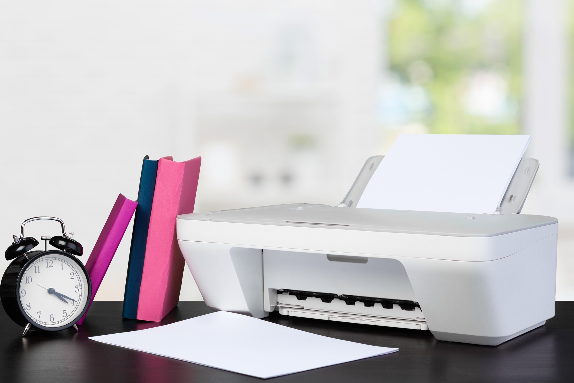 Compact all-in-one printer on a home office desk with books and clock—ideal for showcasing efficient and affordable home printers and scanners.