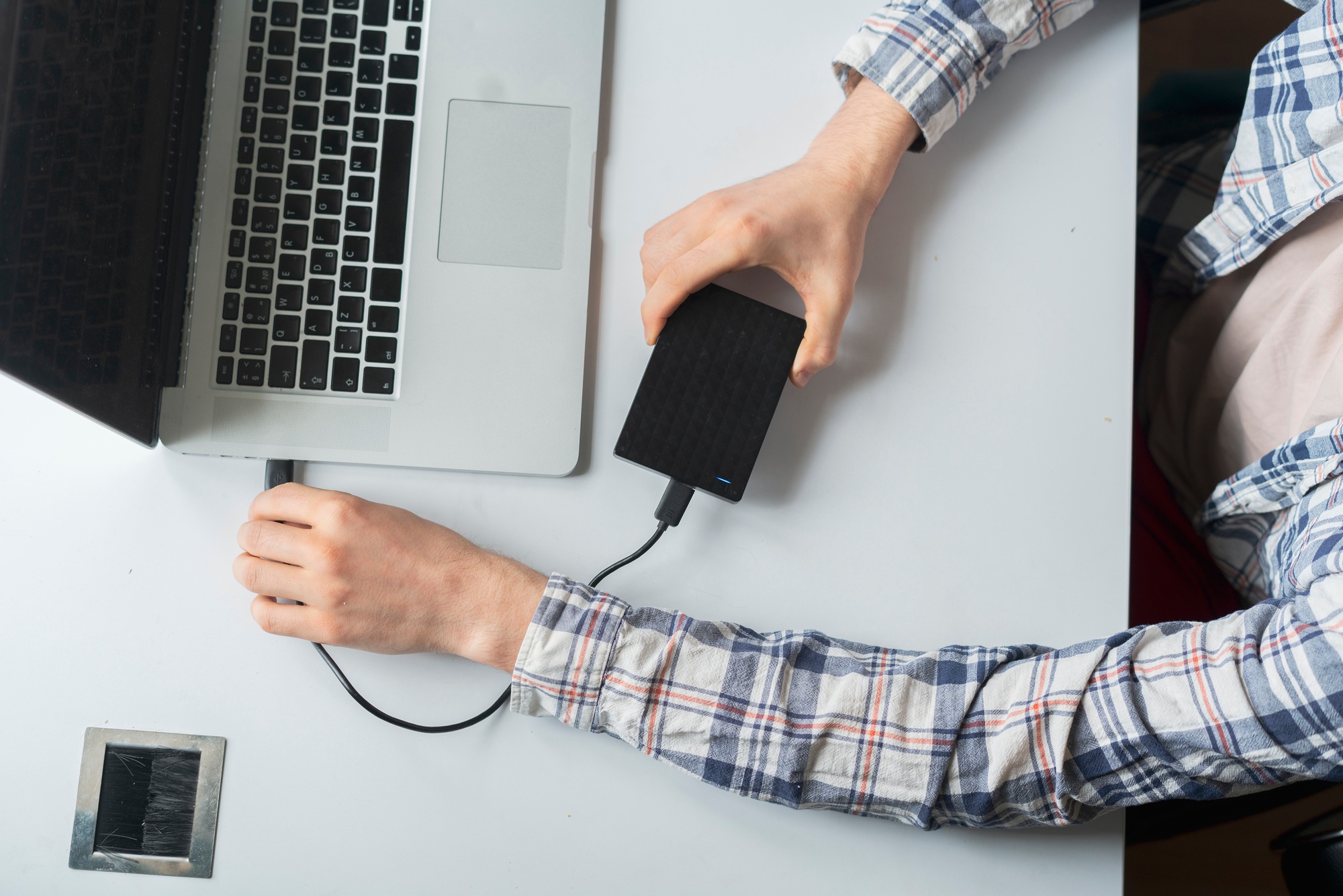 User connecting an external hard drive to a laptop on a desk—highlighting reliable data backup solutions and encouraging professionals to Buy External Storage Drives.