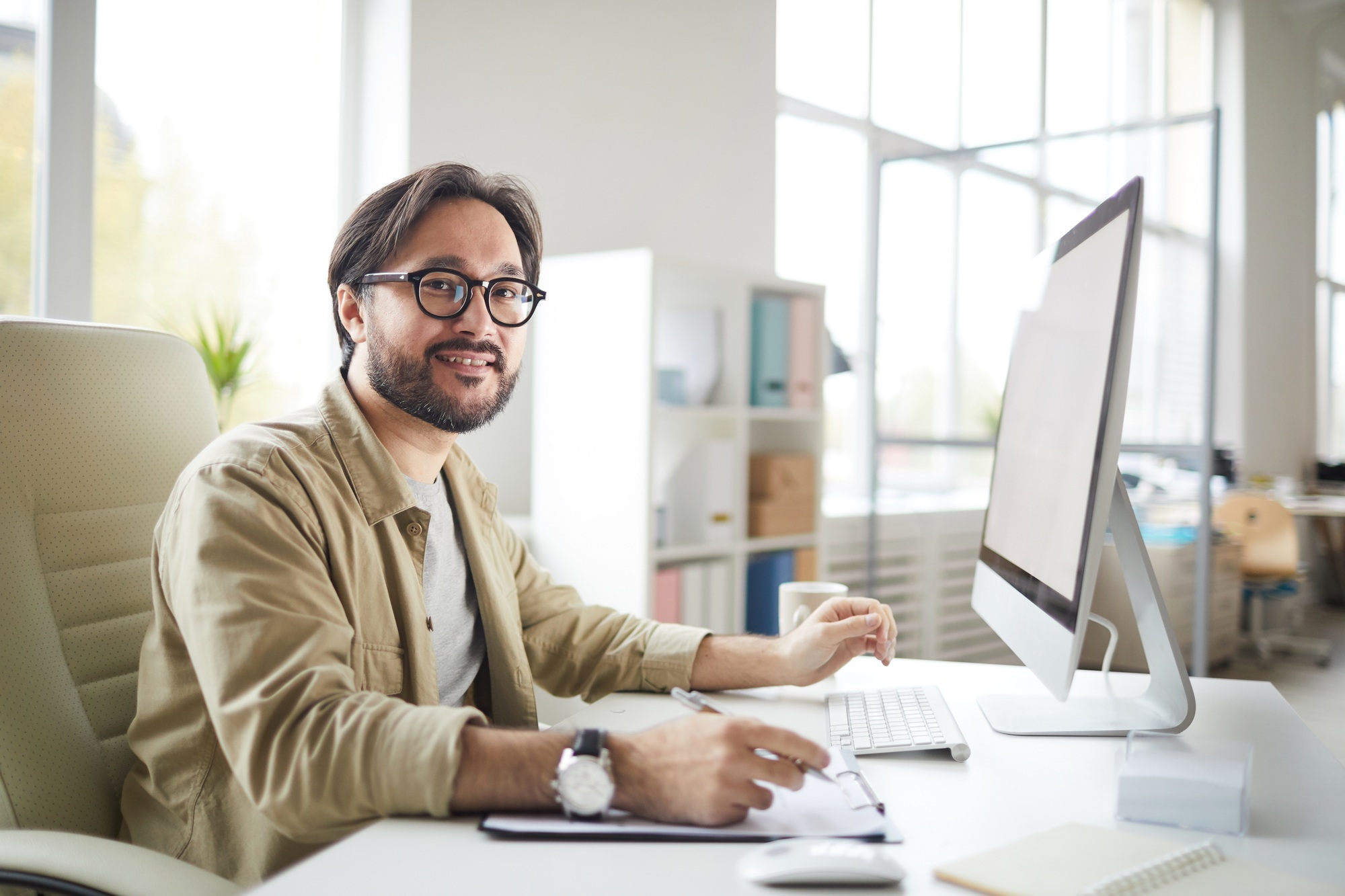 Professional man working at a modern desk setup with desktop and office accessories, representing a well-equipped office tech equipment store environment.

