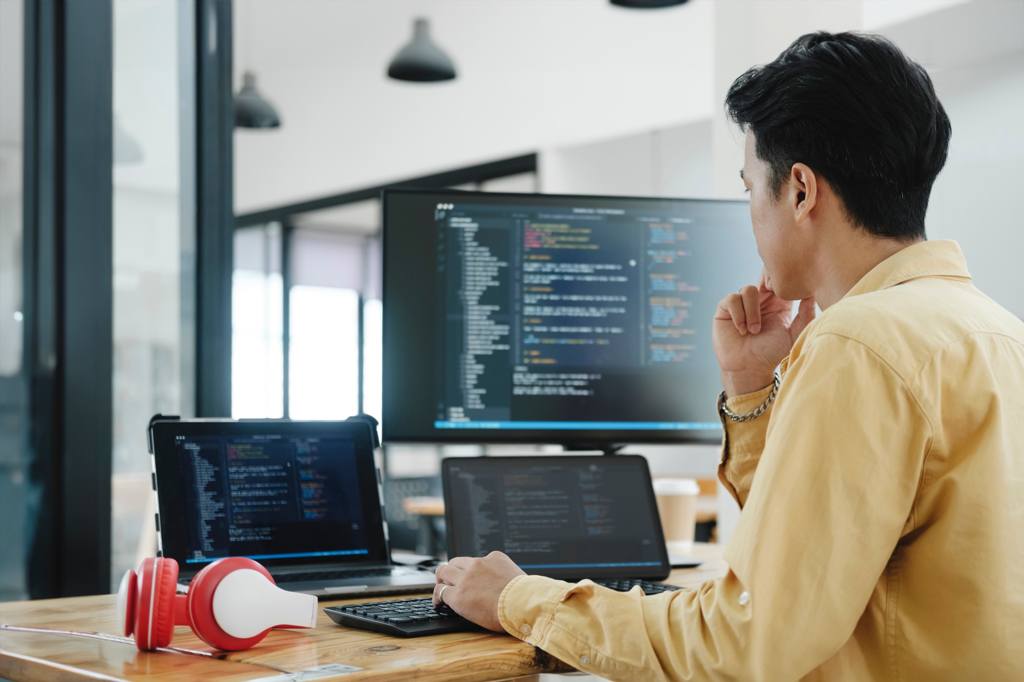 A professional developer working with multiple screens and devices in a modern workspace — showcasing productivity powered by high-performance office desktop computers. 