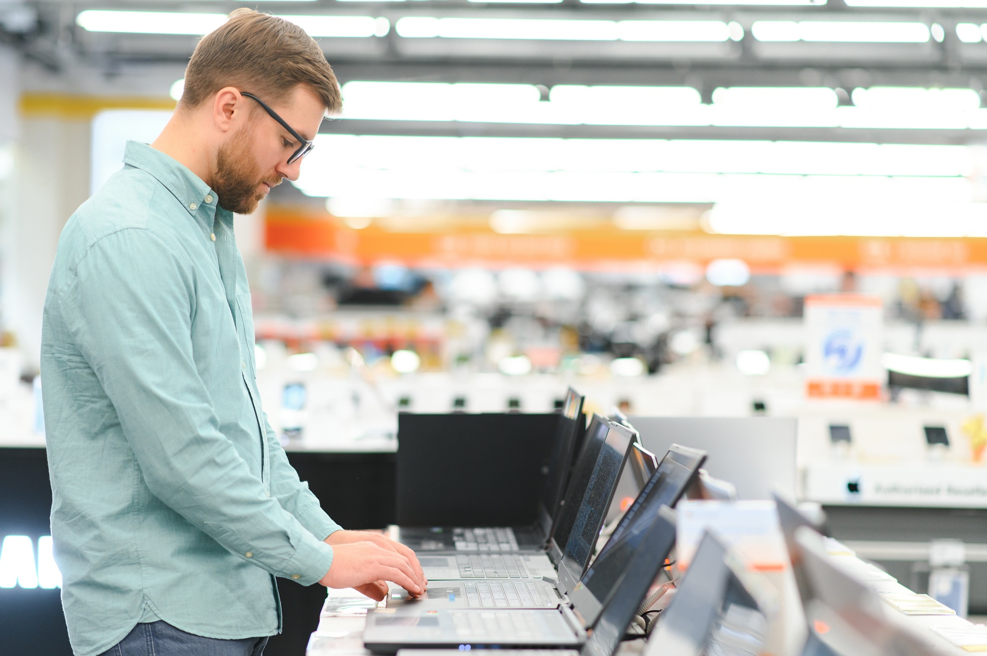 Male customer testing convertible laptops in a tech retail store—ideal for shoppers looking to buy 2-in-1 laptops Florida for work, school, or travel. 