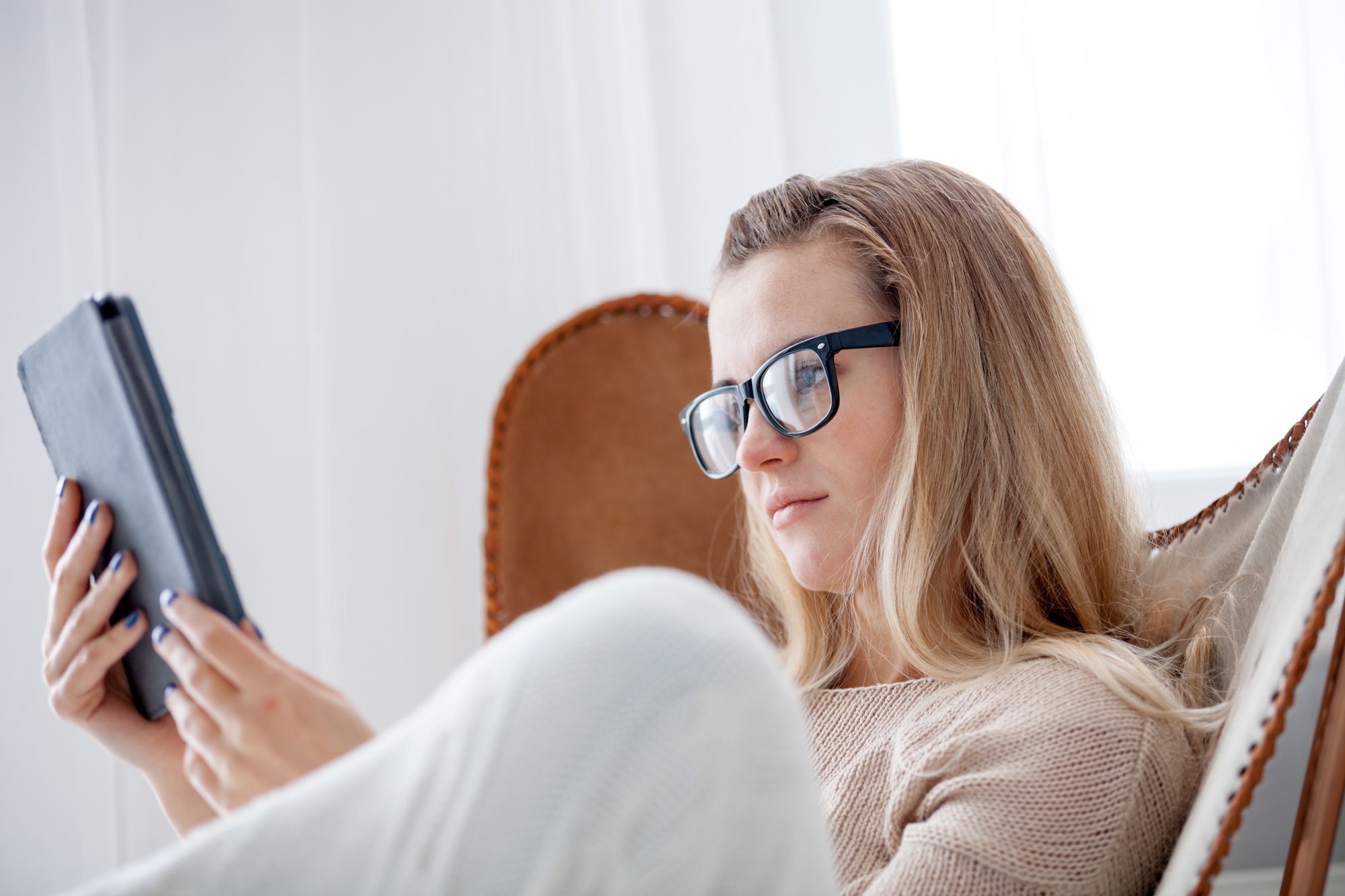 Relaxed woman reading on a digital e-reader while seated comfortably at home—perfect lifestyle visual for campaigns encouraging users to Buy E-Readers Online.